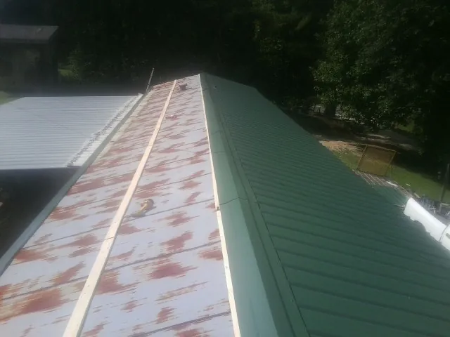 Old rusted panels beside newly installed green metal roofing — Wind Damage Roof Repair by Roofing Brothers in East Marion