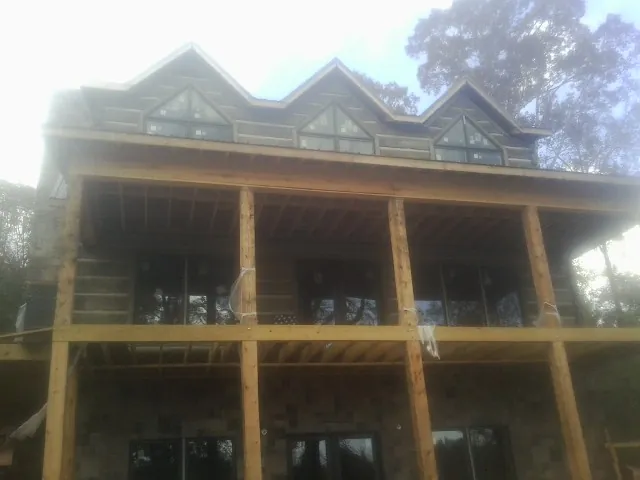 Dormers and porch framing on a large log home under construction — Roof Coating work by our crew in East Marion