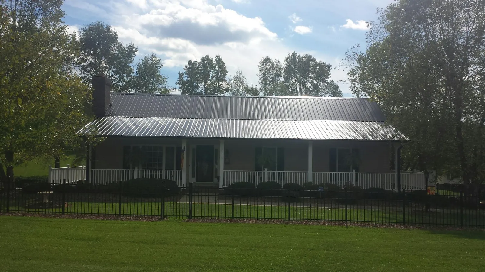 Gray metal roof on a brick ranch with a full width front porch — Gutter Guard Installation work by our crew in East Marion
