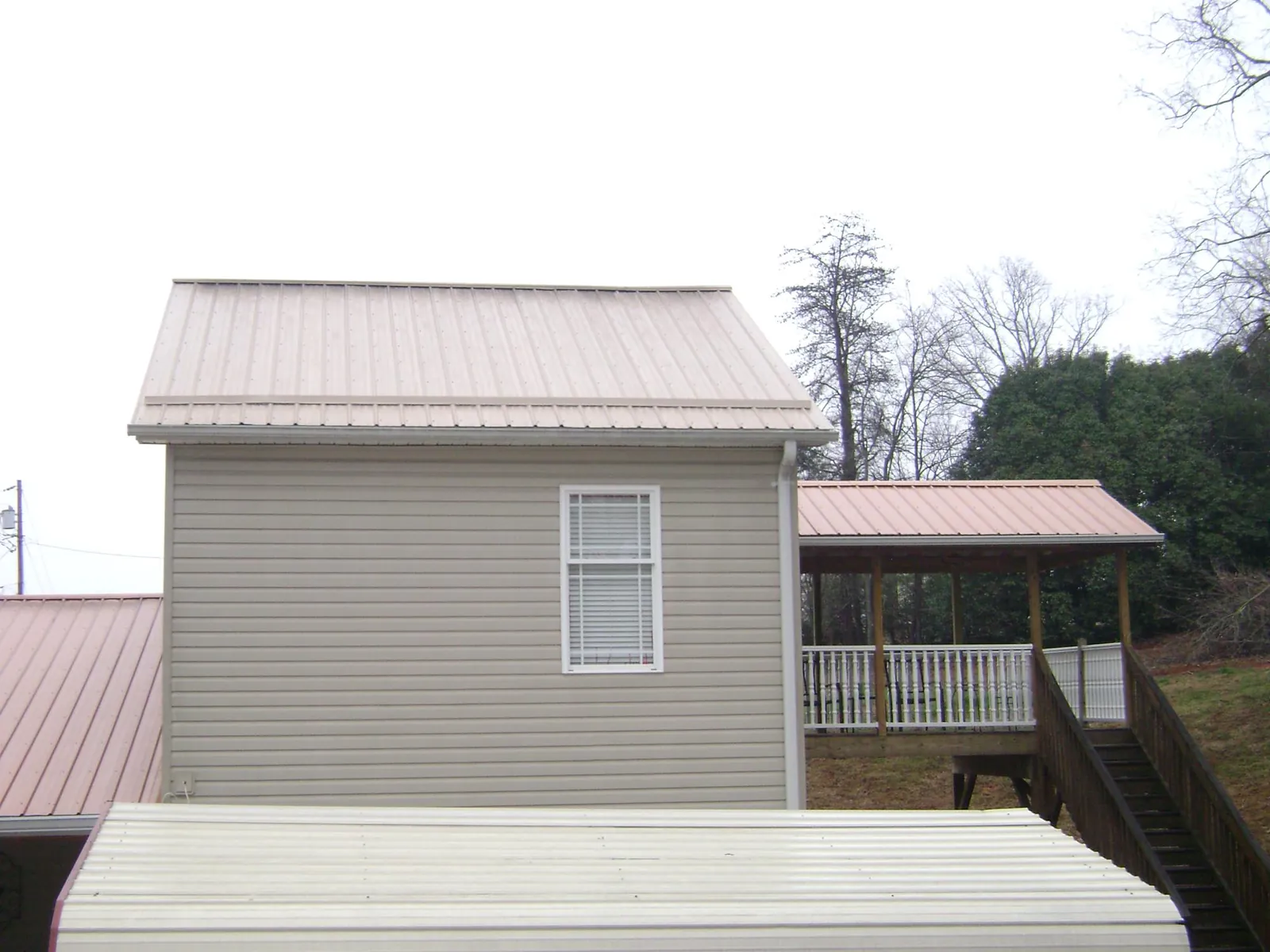 Tan metal roofs on a two story addition and attached porch, from a Roof Replacement job in East Marion