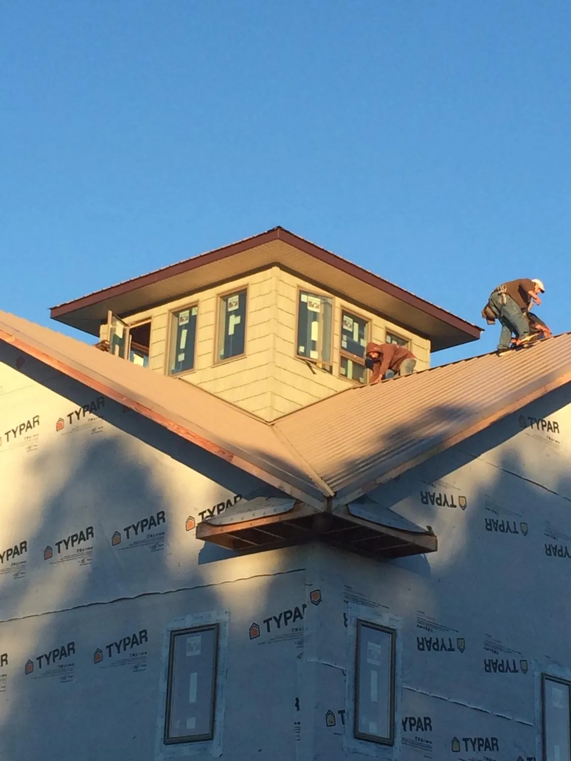 Roofers working around a rooftop cupola on a new metal roof at sunset — Roof Waterproofing in East Marion by Roofing Brothers